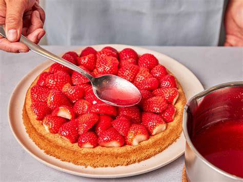 Roter Tortenguss wird vorsichtig auf frischen Erdbeeren verteilt