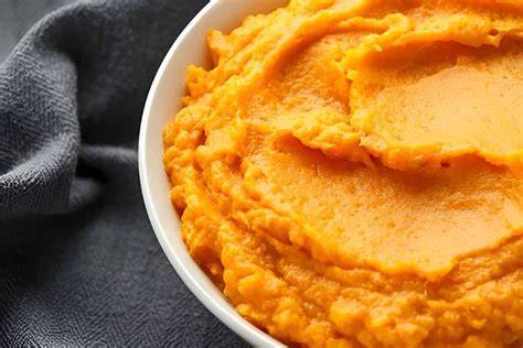 Süßkartoffelpüree in Schüssel, verfeinert mit Butter, fertig zum Servieren