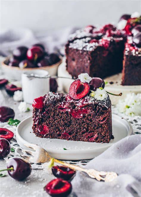 Saftiger veganer Schoko-Kirsch-Kuchen auf Holzbrett mit Kirschen und Zartbitterschokolade