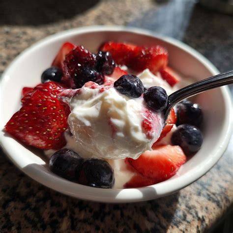 Schüssel mit Joghurt-Sahne-Creme und vorbereiteten Beeren