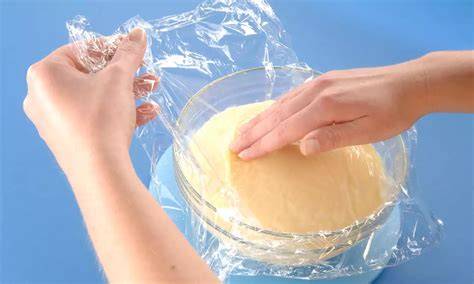 Schüssel mit frisch gekochtem Pudding und Frischhaltefolie