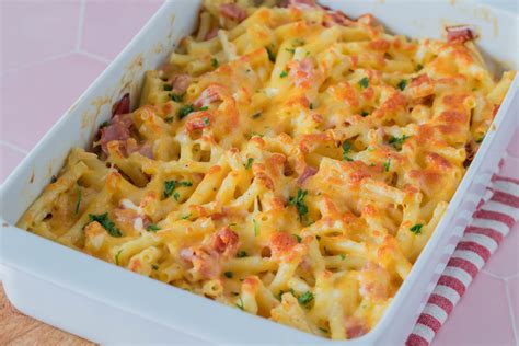 Schüssel mit vorbereiteten Zutaten: Makkaroni, Schinkenwürfel, Tomaten, Ricotta, Käse, Petersilie
