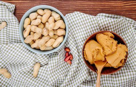 Schale mit Erdnüssen und Glas Erdnussbutter
