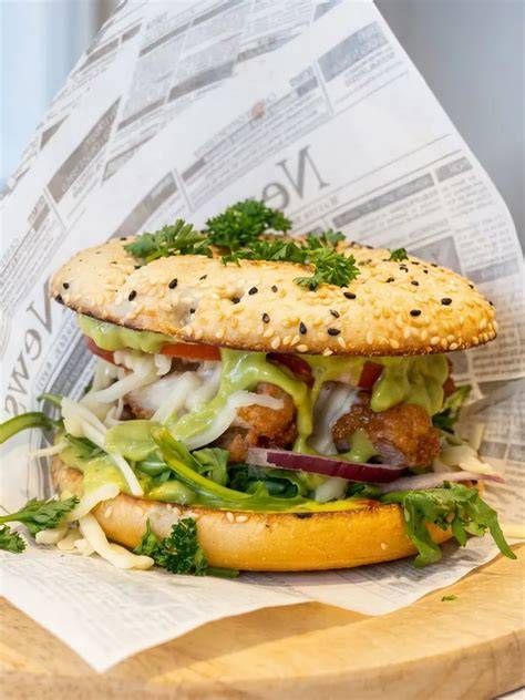 Schichtaufbau: Bun, Sauce, Gurke, Patty, Käse, Tomate, Rucola