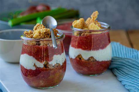 Schichtdessert im Glas mit Rhabarber, Apfel, Erdbeeren, Creme und Pistazien