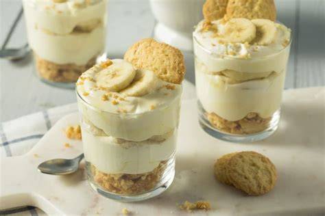 Schichtdessert mit Bananen, Vanillecreme und Keksen in einer Glasschüssel