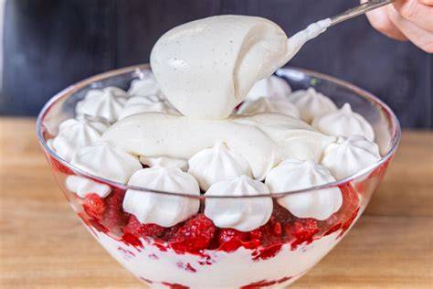 Schichtdessert mit Beeren, Sahne und Baiser in einer Glasschale
