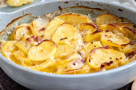 Schichtung von Kartoffeln, Süßkartoffeln und Zwiebeln im veganen Gratin