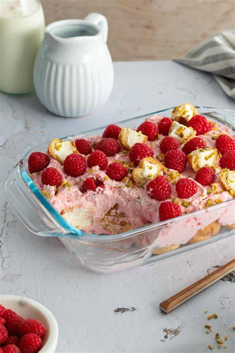 Schichtweise Windbeutel-Dessert mit Himbeeren und Pistazien dekoriert
