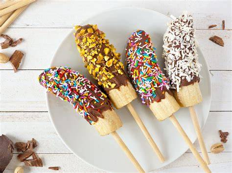 Schoko Bananen Spieße mit bunten Toppings auf Servierplatte