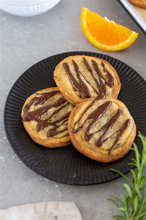 Schoko Orangen Cookies mit einer Dekoration aus weißer Kuvertüre und Orangenzeste