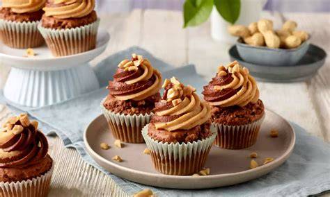 Schoko-Erdnuss-Cupcakes auf einem Teller, dekoriert mit gehackten Erdnüssen