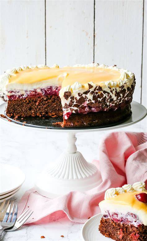 Schoko-Kirsch-Torte auf einer Tortenplatte mit Schokoraspeln und Kirschen