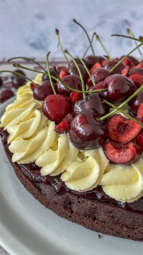 Schokokuchen mit rosa Zuckerglasur und frischen Kirschen