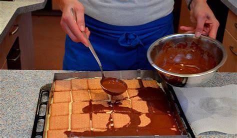 Schokoladenglasur wird auf Haselnuss-Nougat-Kuchen verteilt
