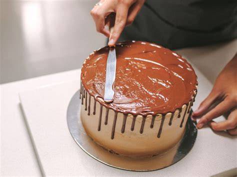 Schokoladenglasur wird auf den Kuchen gestrichen