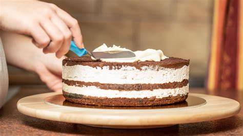 Schokoladenglasur wird mit einem Spatel auf Kuchen verteilt
