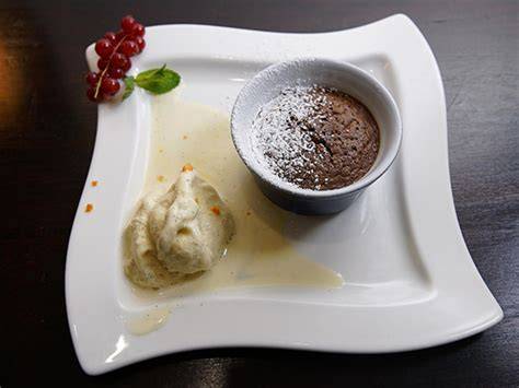 Schokoladensoufflé angerichtet mit Vanillesauce und Eis