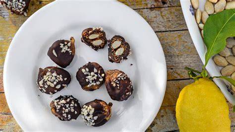 Schokolierte Mandeln mit Dulcey, angerichtet neben Gelbfrüchten und Pralinen