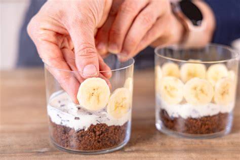 Schokosauce über Bananenscheiben im Glas träufeln