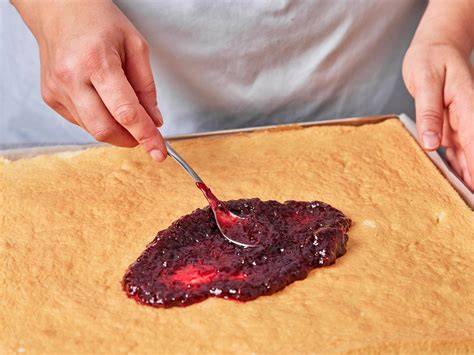Schrittbild: Biskuitplatte mit Preiselbeeren und Sahne bestreichen