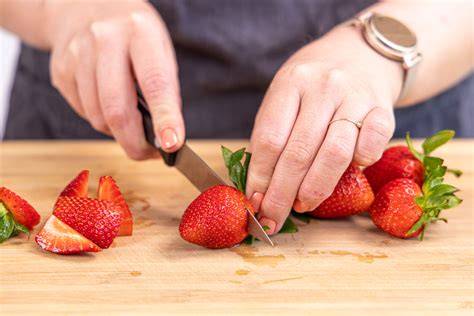 Schrittgrafik: Erdbeeren putzen, in Scheiben schneiden, mit Zitronensaft mischen