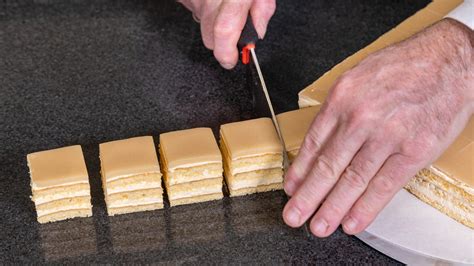 Schrittweises Überziehen von Petit Fours mit Schokolade auf einem Gitter