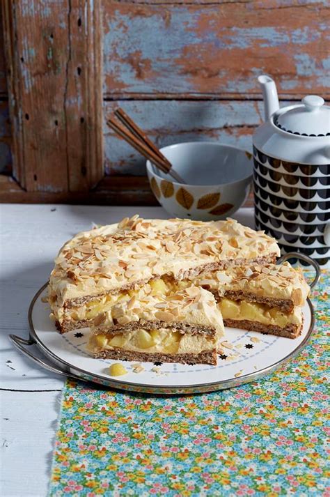 Schwedische Apfel-Mandel-Torte auf einem rustikalen Holztisch, umringt von Äpfeln und Mandeln