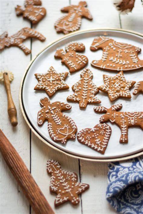 Schwedische Pepparkakor, Zutaten und gebackene Plätzchen auf einem rustikalen Holzbrett