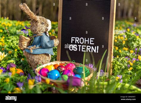 Selbst gemachte, bunt verzierte Osterhasen auf einem Ostertisch neben Eiern und Frühlingsblumen