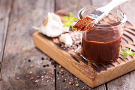 Selbstgemachte BBQ Sauce neben Grillfleisch und Beilagen auf einem gedeckten Tisch