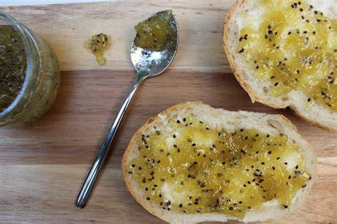 Selbstgemachte Kiwi-Vanille-Marmelade im Glas mit Frühstücksbrötchen