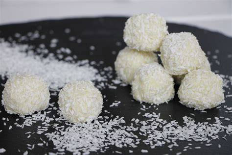 Selbstgemachte Kokospralinen auf weißem Teller mit Mandeln und Kokosflocken