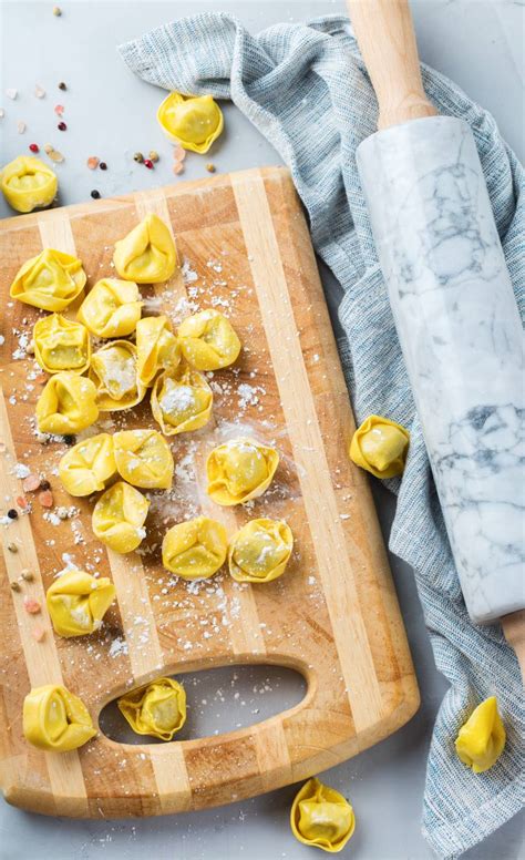 Selbstgemachte Tortellini auf einem Nudelbrett mit Nudelmaschine