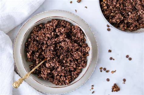 Selbstgemachtes Schoko Knuspermüsli auf einem Holzbrett mit frischen Früchten