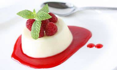 Servierbeispiel weiße Schokolade Panna Cotta mit Himbeersoße und Minze
