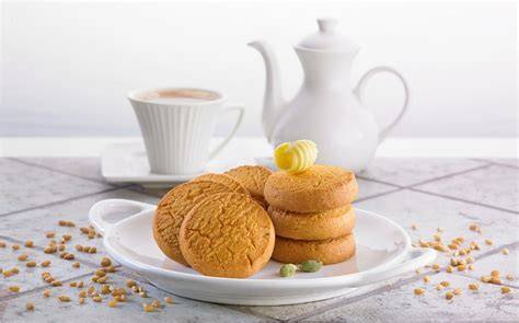 Servierte Kardamomkekse auf einer Plätzchendose mit Tasse Tee
