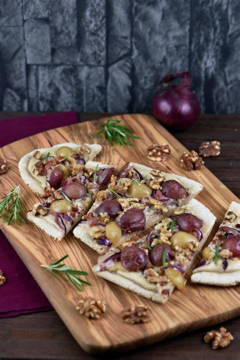 Serviervorschlag: Apfel-Zimt-Flammkuchen in Stücke geschnitten auf Holzbrett mit Zimtstreuern