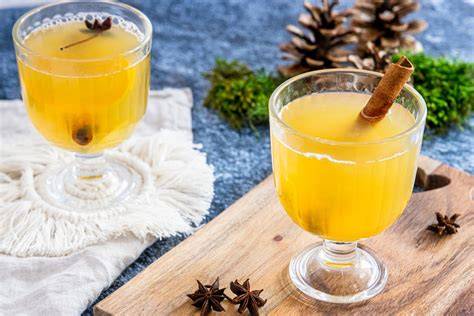 Serviervorschlag: Becher mit weißem Glühwein, Apfelsternen, Vanilleschote und Zimtstange