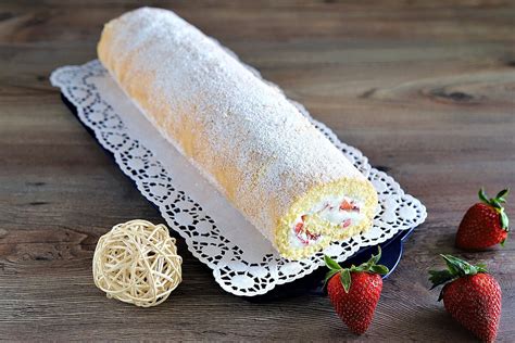 Serviervorschlag: Biskuitrolle mit Puderzucker und Erdbeeren auf Tortenplatte