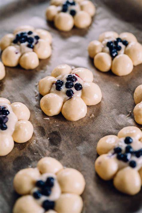 Serviervorschlag: Hefeblumen mit Puderzucker, Blaubeeren und Erdbeeren auf Kuchentafel