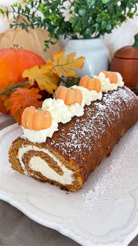 Serviervorschlag: Kürbis-Biskuitrolle mit Puderzucker, Marzipankürbissen und Schokoblättern