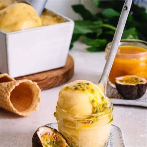 Serviervorschlag: Kugel Passionsfrucht-Sorbet im Glas mit Minze