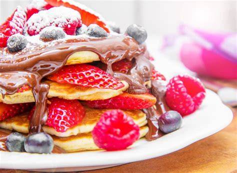 Serviervorschlag: Pancake-Board mit Beeren, Ahornsirup, geschmolzener Schokolade