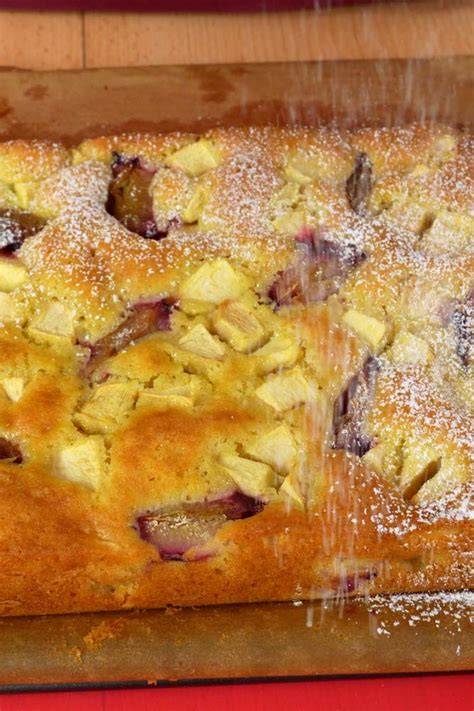 Serviervorschlag: Stück Apfel-Pflaumen-Kuchen mit Sahne und Puderzucker