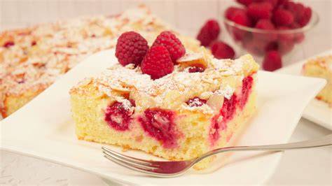 Serviervorschlag: Stück Himbeer-Quark-Kuchen mit Puderzucker und Minze