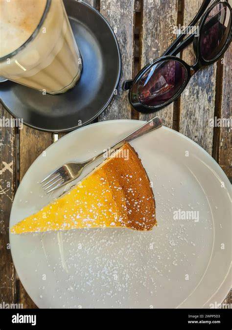 Serviervorschlag: Stück Käsekuchen mit Puderzucker und Kaffee