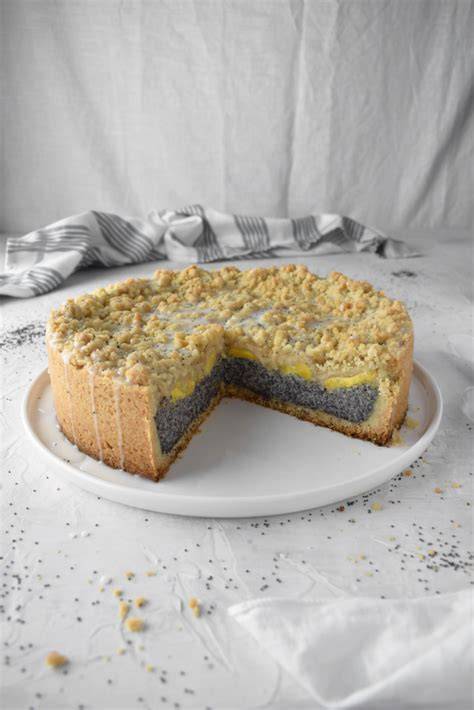 Serviervorschlag: Stück Mohnkuchen mit Pfirsich, Staubzucker und Sahne auf Teller