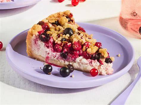 Serviervorschlag: Stücke Früchte-Schmand-Kuchen auf Tellern mit Beeren und Minze