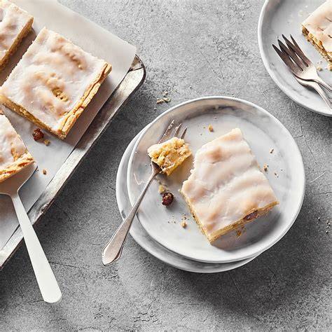 Serviervorschlag: Stücke vom Karamell-Blechkuchen auf Tafel mit Haselnüssen